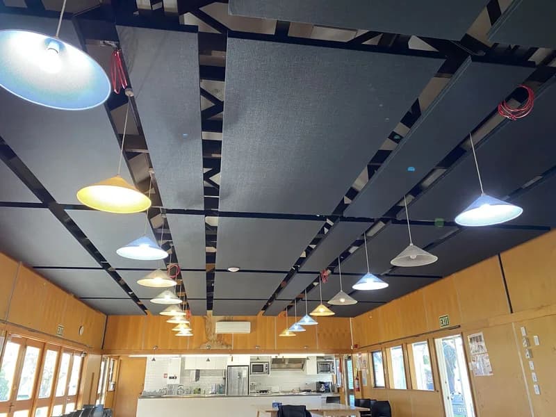 Finished black and grey acoustic panels on exposed ceiling battens above the Hopepa kitchen and timber walls