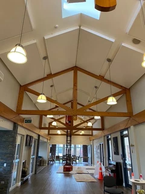 Finished high vaulted ceiling with timber trusses and white acoustic panels above the Somerset activity room